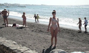 Busty MILF is walking almost naked on the public beach making everyone blush